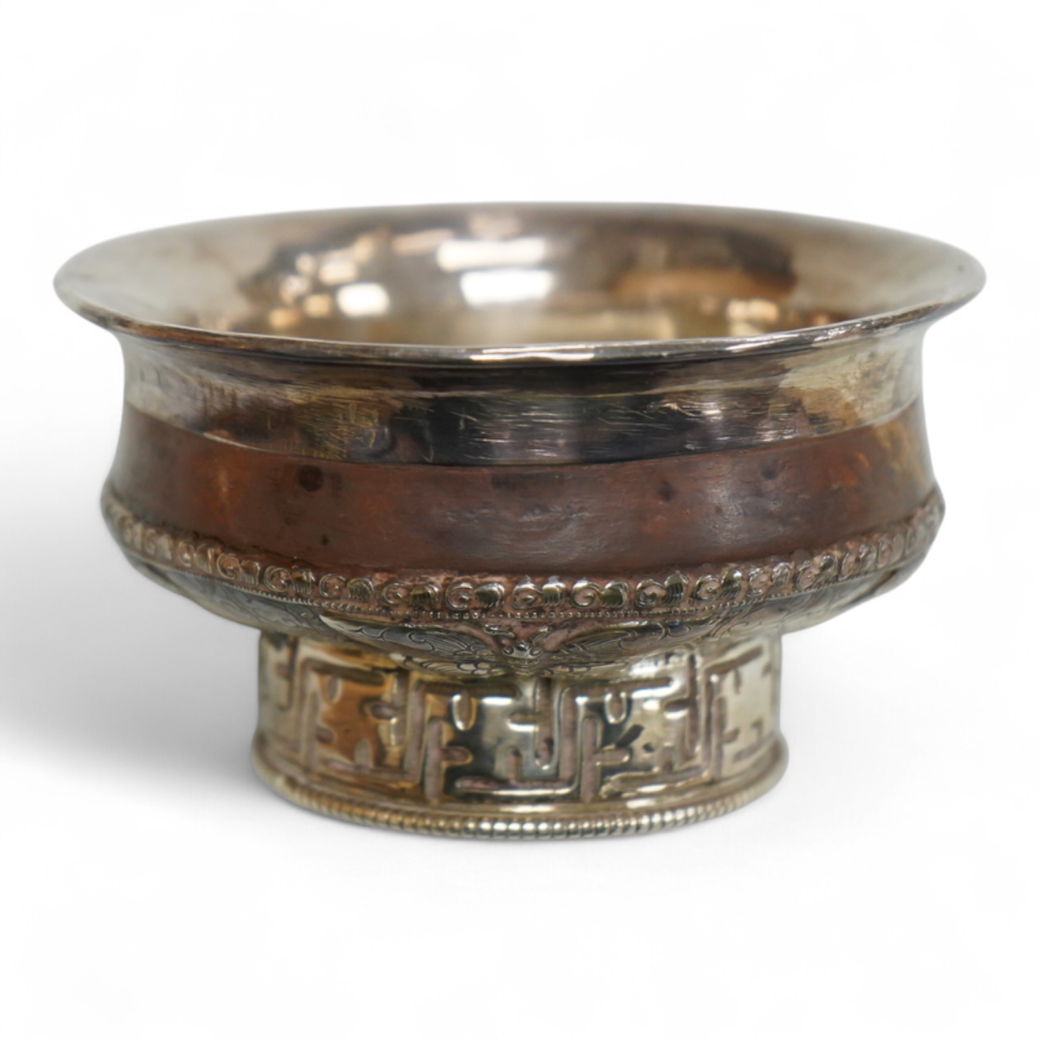 An antique Tibetan white metal mounted burl wood tsampa bowl, on a circular foot, diameter 99mm.